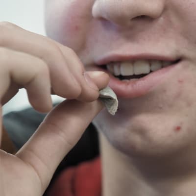 Mieshenkilö laittaa nuuskapussin huuleen