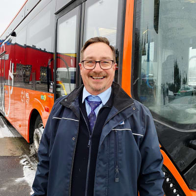 Frank Ahrenberg framför en orange elbuss.