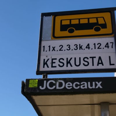 Lähikuvassa bussipysäkin kyltti ja linjanumerot