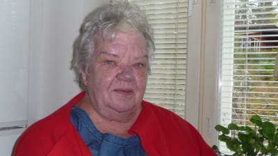 Rosie Westerlund vid sitt köksfönster, pelargoner och bordslampa  på fönsterbrädet