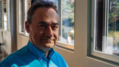 Ben Furman står med en blå skjorta vid ett fönster där ljuset strömmar in.