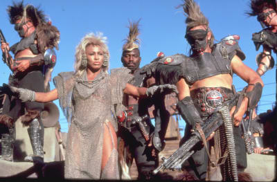 Tina Turner med stora örhängen och apokalyptiska kläder i filmen Mad Max III år 1985.