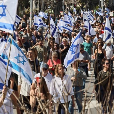 Demonstranter med flaggor under en demonstration mot regeringens kontroversiella lagförslag om rättsreform i Tel Aviv.