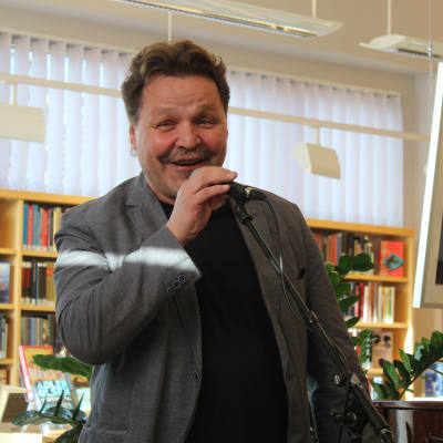 Arto Huhtinen puhuu mikrofoniin kirjastossa
