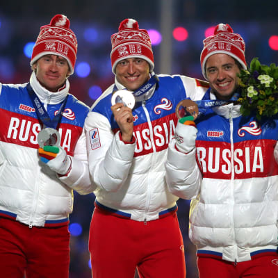 De ryska medaljörerna på femmilen i Sotji poserar på prispallen.