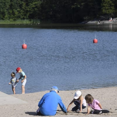 Barn och vuxna umgås på stranden vid Bodom träsk i Esbo.