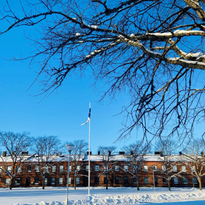Nylands brigad med flaggan i topp en solig vinterdag med knallblå himmel