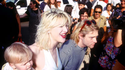 Courtney Love och Kurt Cobain med lilla Frances Bean på MTV Video Music Awards 1993 omgivna av folk.
