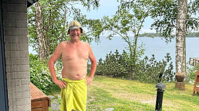 Timo Lindgren från Bastusällskapet står utanför en bastu med handuk runt midjan.