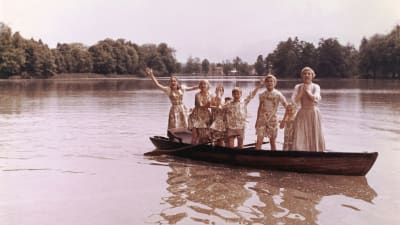 Maria (Julie Andrews) och alla von Trapp-barnen står upp i en roddbåt.