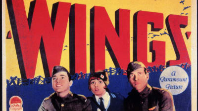Elokuvan The Wings - Siivet -juliste, jossa keltaisella pohjalla isoilla punaisilla kirjaimilla Wings ja sitä kiertävät lentokoneet. Etualalla univormupukuisia elokuvan roolihenkilöitä katsomassa yläviistoon.
