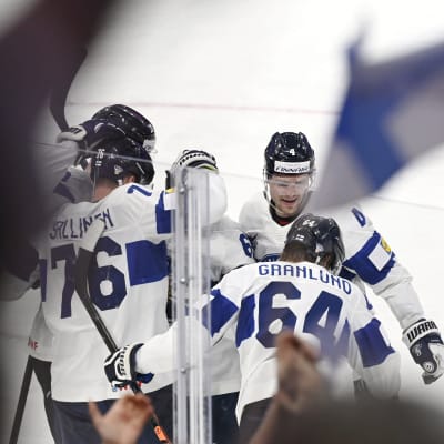 Finlänska ishockeyspelare i ett hav av flaggor.