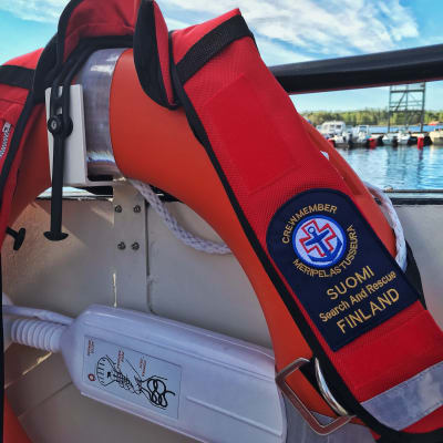 Suomen Meripelastusseuran logolla varustetut pelastusliivit pelastusrenkaan päällä. 