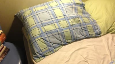 dyna och skrynkliga lakan i en obäddad säng