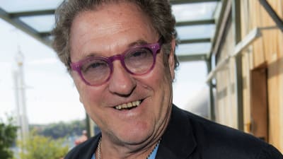 Leende man med rosa glasögon och svart kavaj