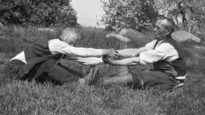 Två män leker leken "vetukapul", som är en slags dragkamp. Bilden är tagen 1929 i Strömfors, Kungsböle.