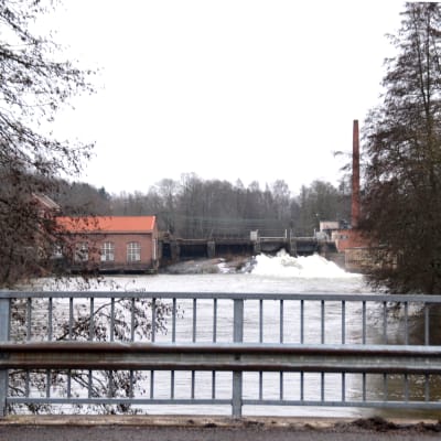 En bild tagen från en bro som föreställer en konstgjord fors där det forsar vatten. Runtom finns tegelhus.
