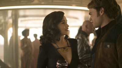Qi'ra (Emilia Clarke) och Han Solo (Alden Ehrenreich) står och ser på varandra i en bar.