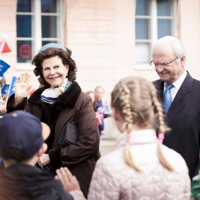 Drottning Silvia och kung Carl XVI Gustaf promenerar och vinkar till publiken på Salutorget i Helsingfors.