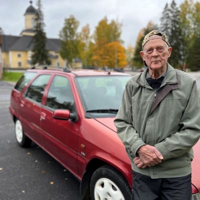Matti Ikonen (94) nojaa autonsa konepeltiin Puumalan keskustan parkkipaikalla.