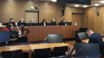 Helsingfors hovrätt med domarna bakom skranket, åklagaren till vänster och försvarsadvokat och åtalad till höger