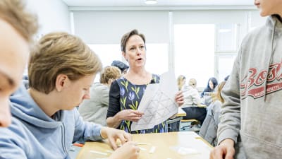 Lärare förklarar saker för elever vid en pulpet