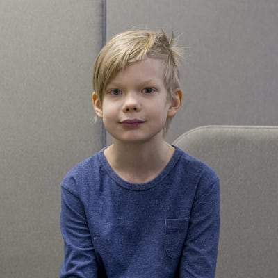 Lauritsalan koulun 3.-luokkalainen Aleksi Liutu istuu koulun oleskelutilassa ja katsoo kameraan. 