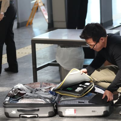 En man tar ut sin bärbara dator ur en kappsäck på golvet på Ataturk Airport, i Istanbul.