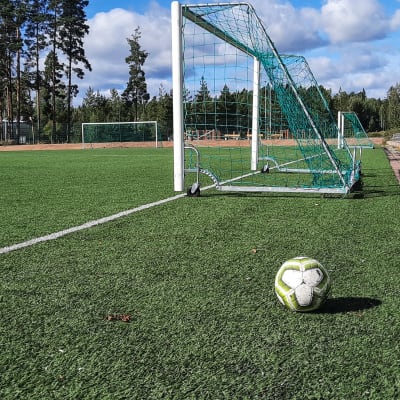 En fotboll bredvid ett mål på en fotbollsplan.