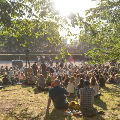 Människor sitter i en fullsatt park.