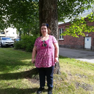 Närvårdare Emma Karlsson står framför ett träd. 