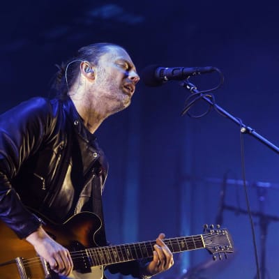 Radioheadin laulaja Thom Yorke lavalla kitaran ja mikrofonin kanssa.