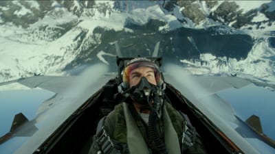 En man i cockpiten till ett stridsflygplan som befinner sig upp och ner i luften.