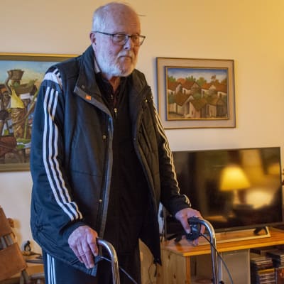 En äldre man går med sin rullator i sin bostad.