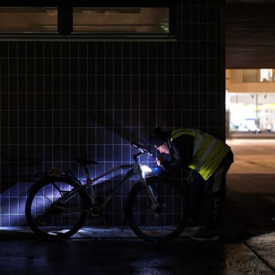 Ilkka Pulkkinen tutkii pyörää otsalampun valossa.