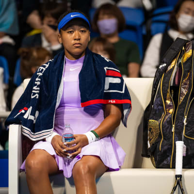 Naomi Osaka istuu tenniskentän laidalla.