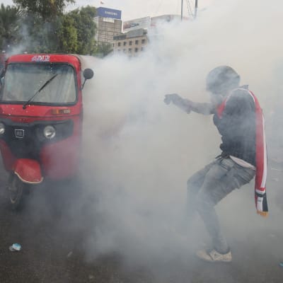 En demonstrant i ett moln av tårgas i Bagdad