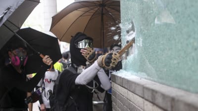 Demonstrant krossar ett skyltfönster i Hongkong. 
