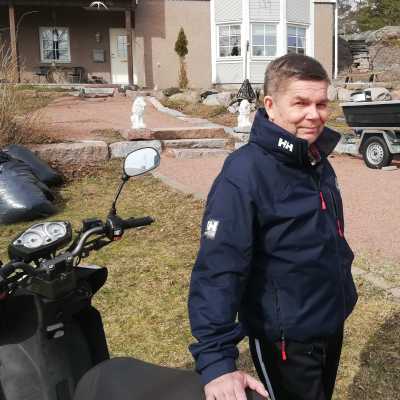 En man står vid sin moped på hemgården i Kapellhamnen i Hangö.