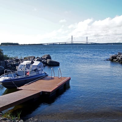 En båt som ligger förtöjd vid en brygga, men utsikt över Replotbron.