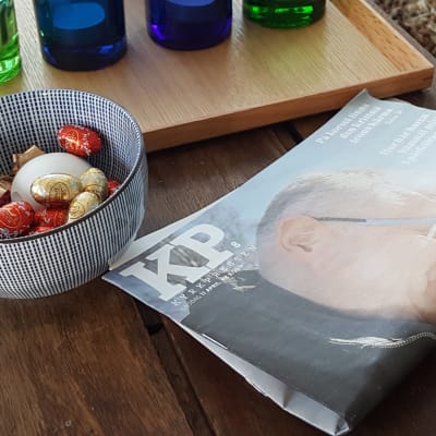 Kyrkpressen tidningen ligger på ett bord vid en skål med påskägg