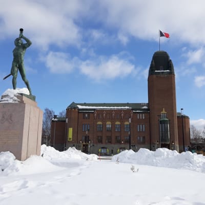 Joensuun kaupungintalo seisoo lumen keskellä maaliskuisena aurinkoisena päivänä.