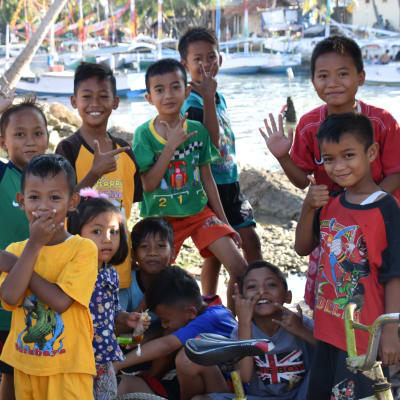 Indonesiska barn poserar för kameran. Många av dem visar olika tecken med fingrarna.