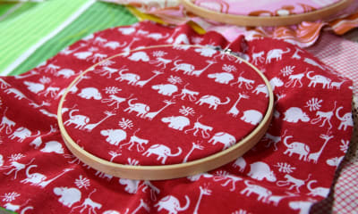Syring med ett återvunnet rött tyg med mönster av små vita elefeanter och giraffer.