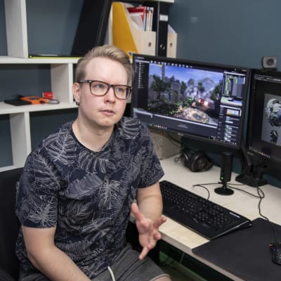 Teemu Jyrkinen istuu tietokoneen näyttöjen ääressä. Näytöillä tietokonepeli.