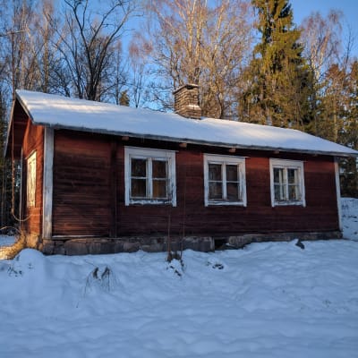 Den gamla lärarstugan i Björkkulla i Pojo från sidan i vinterlandskap.