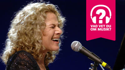 Carole King sjunger i en mikrofon.