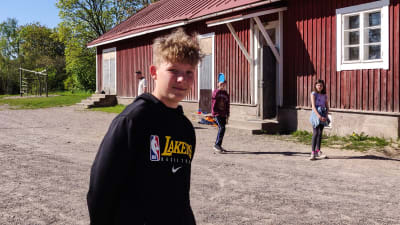 En ung pojke står på en skolgård.