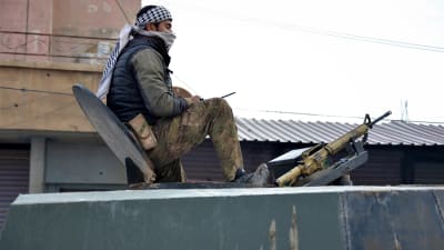 En kurdisk soldat sitter på taket till en pansarfordon. Bredvid sig har han en automatkarbin.