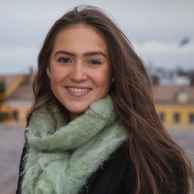 Porträttbild på Finlands lucia framför en julgran.
